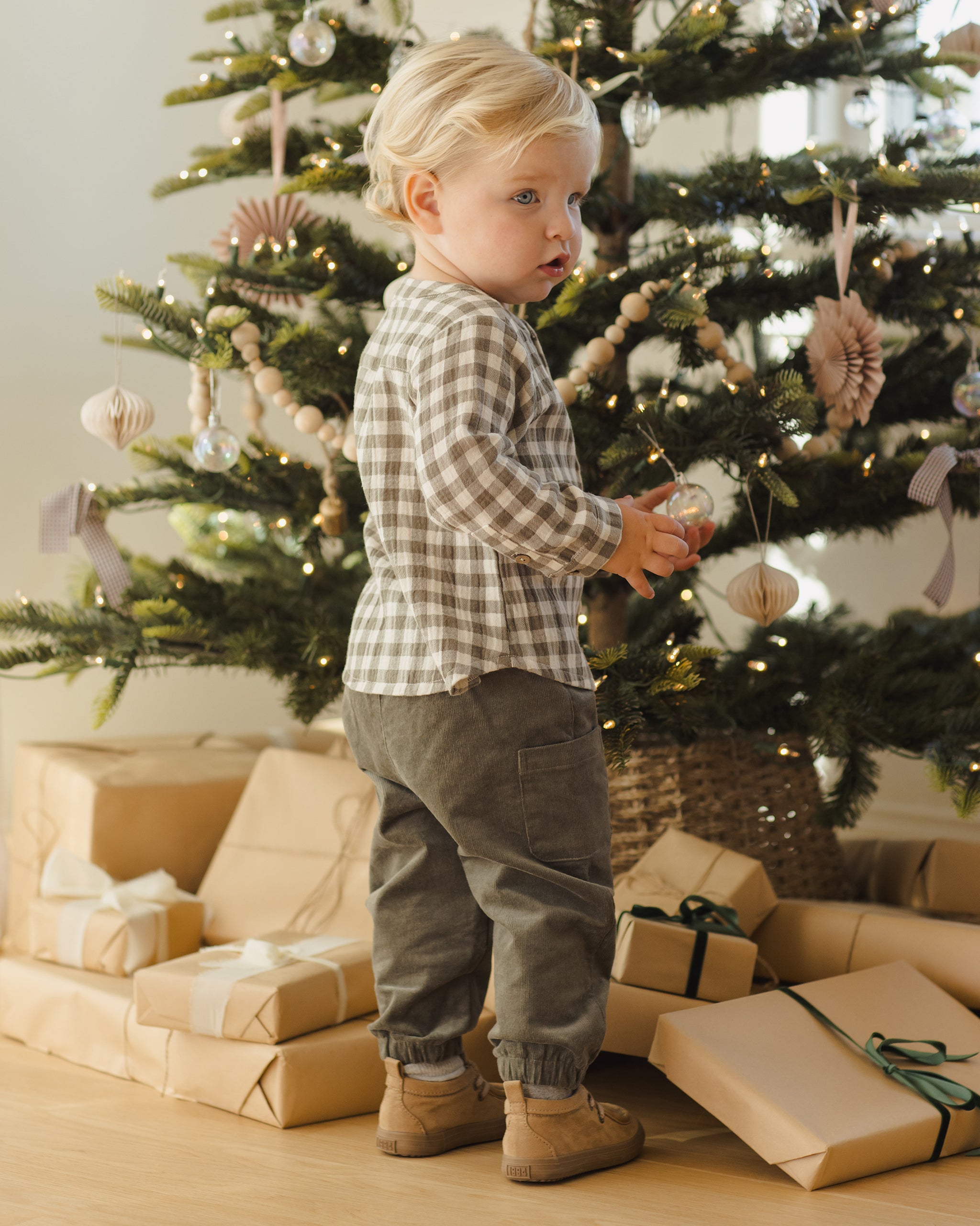 Child standing in front of a decorated Christmas tree with presents underneath