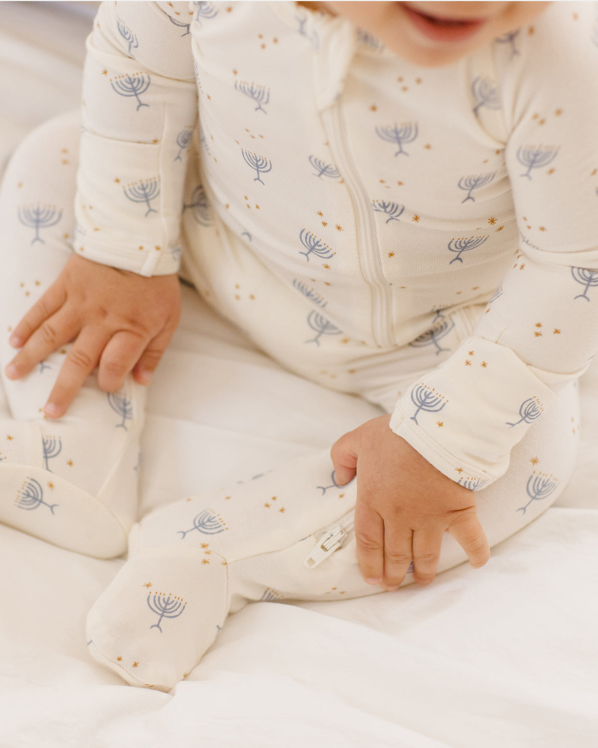 Baby in a white onesie with blue floral patterns on a white background