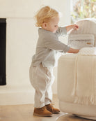 Child playing with a beige armchair in a softly lit room