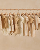 Row of children's clothing on hangers against a beige wall