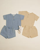 Two children's outfits, one blue and one beige, with matching shorts and a toy on a light background.