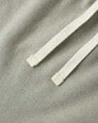 Close-up of a light sage green fabric with a contrasting off-white braided drawstring.