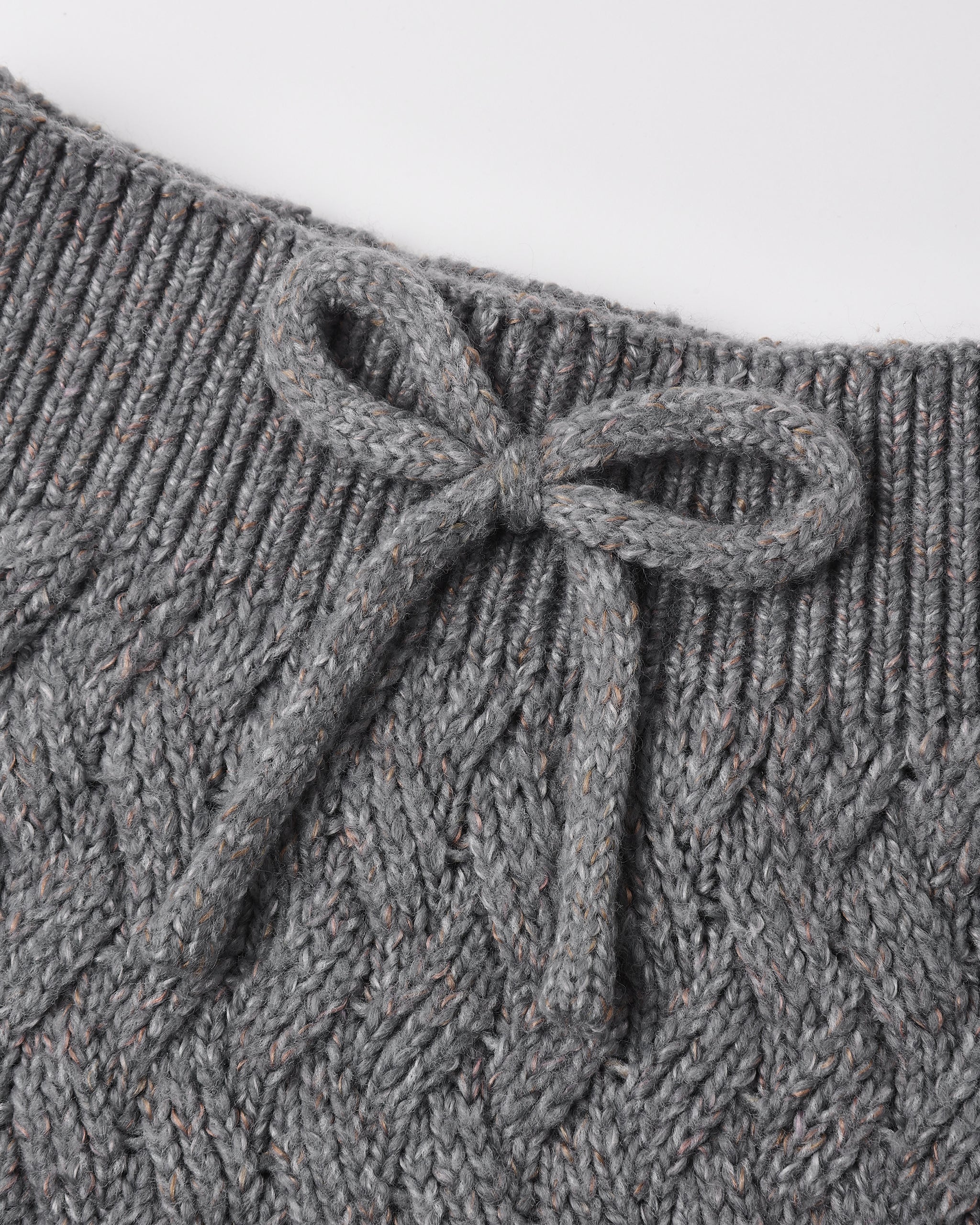 Close-up of a gray cable-knit garment with a ribbed neckline and a knotted bow detail at the center front.