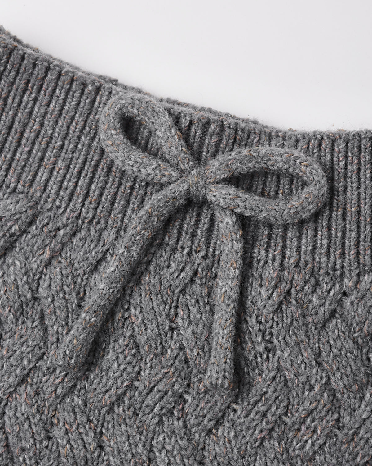 Close-up of a gray cable-knit garment with a ribbed neckline and a knotted bow detail at the center front.