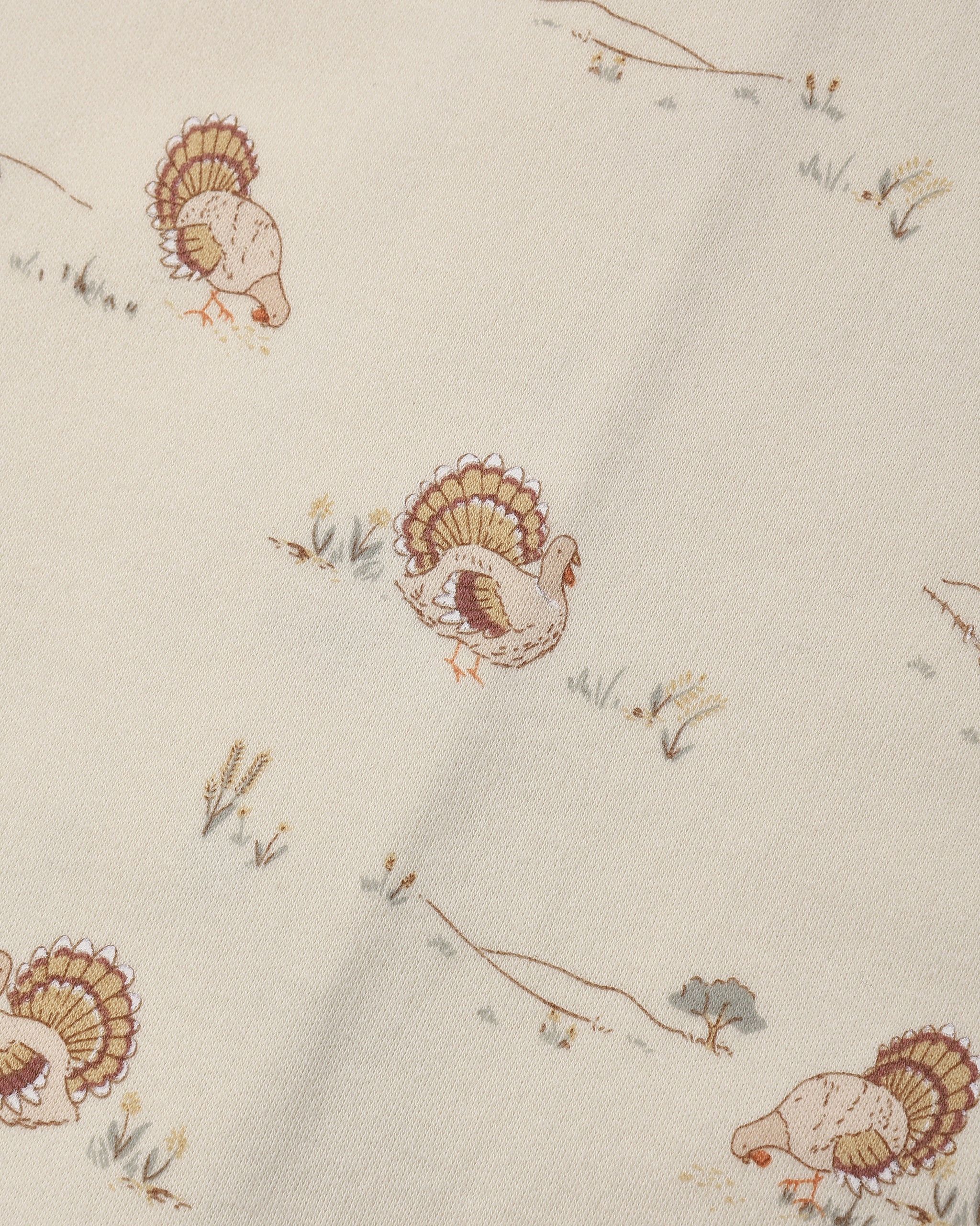 Fabric with charming tiny illustrated turkeys scattered across a soft cream background.