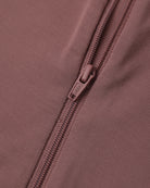Close-up of a dusty rose pink zippered garment, showing the fabric texture and a matching pull tab with the brand name 'SOL'S' visible.