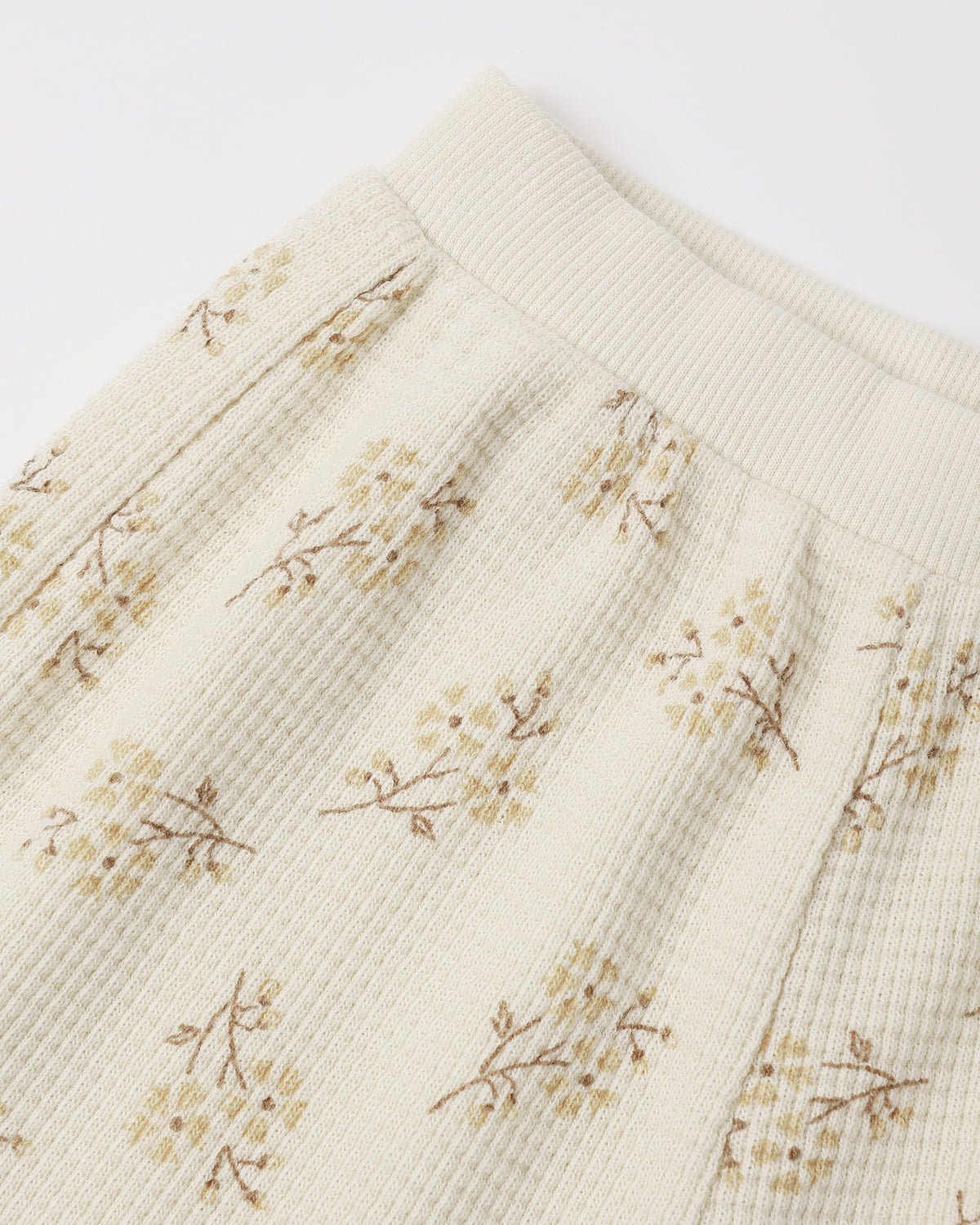 An off-white ribbed cotton toddler legging featuring a delicate, vintage-style small floral print with soft yellow and brownish stems.