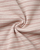 A close-up of a soft knit fabric with a dusty pink and white horizontal stripe pattern, arranged in a central swirl to highlight its texture and drape.
