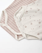 Two soft baby bodysuit fabrics laid flat on a white background: one with thin dusty pink and cream stripes, and one in warm off-white with small scattered floral motifs.