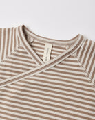 Close-up of a baby wrap top with horizontal beige and off-white stripes, featuring a V-neck and a visible 'CONCEPT MATE' brand tag.