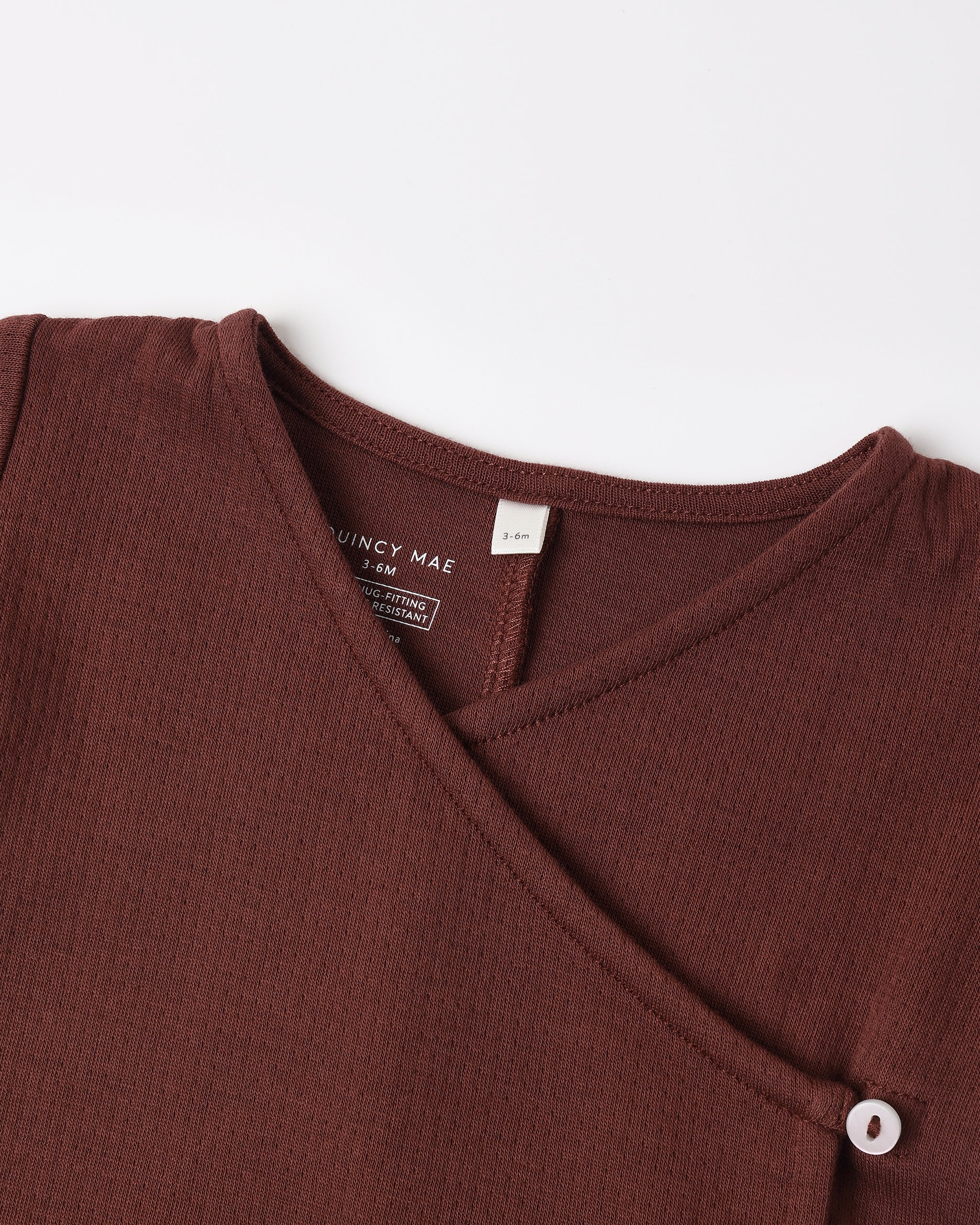 A dark brown Quincy Mae baby wrap-around top featuring a side button closure.