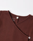 A dark brown Quincy Mae baby wrap-around top featuring a side button closure.