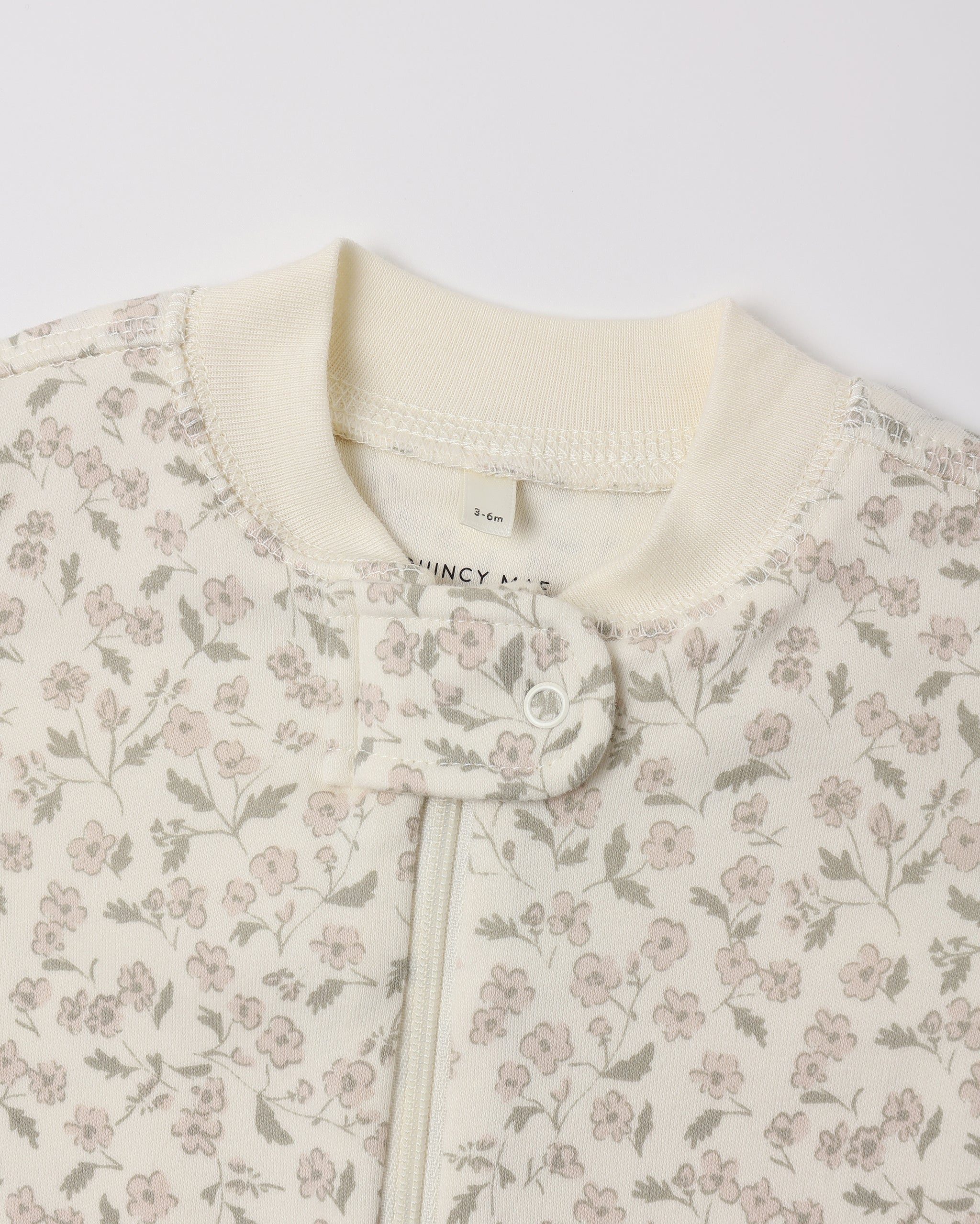 Close-up of  Quincy Mae Zip Long Sleeve Sleeper Footie in the "French Garden" print on an ivory background