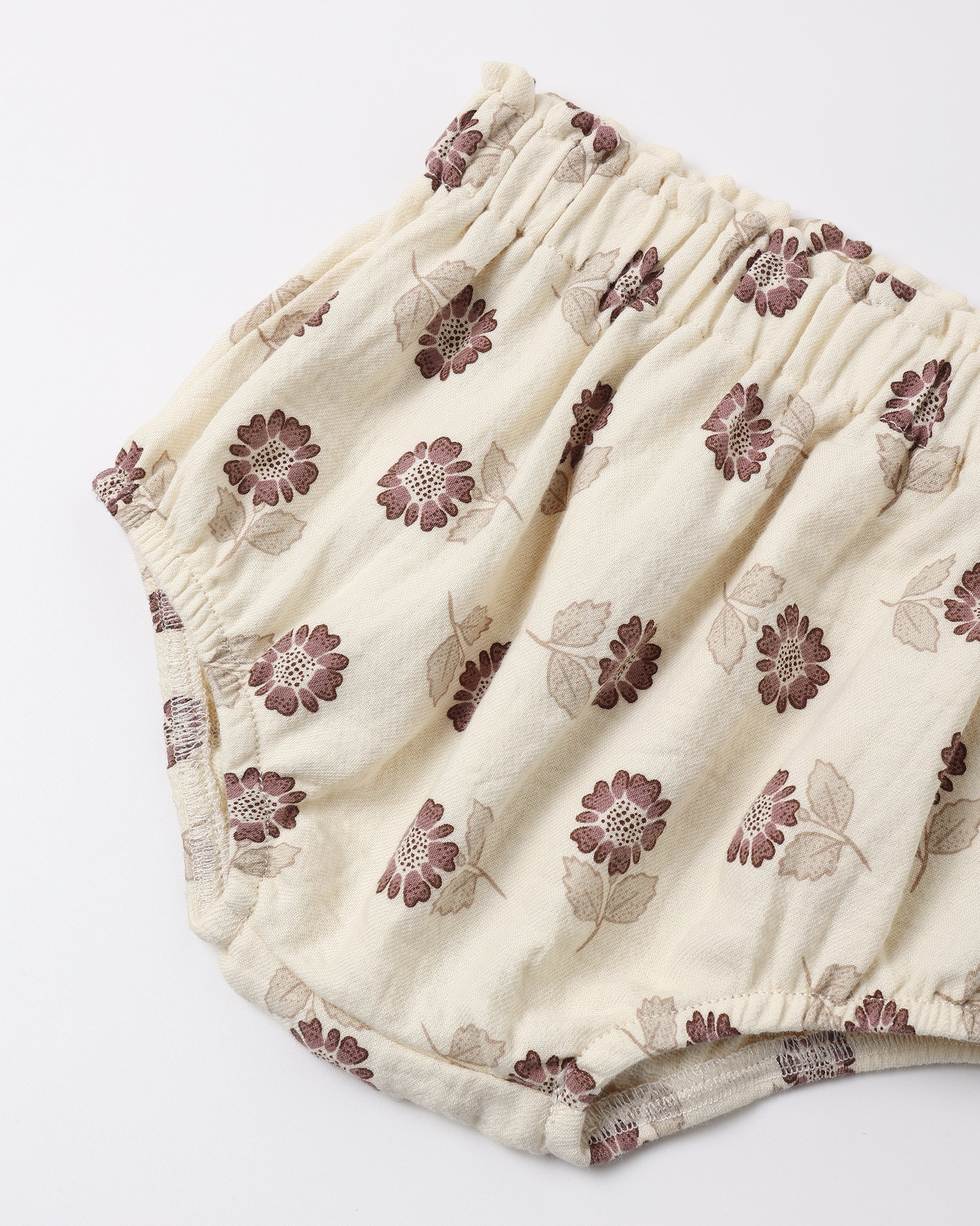 Cream-colored cotton diaper cover with a brown and beige floral pattern, featuring an elastic waistband.