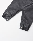 Close-up of dark gray corduroy pants with buttoned cuff details, laid flat on a white background.