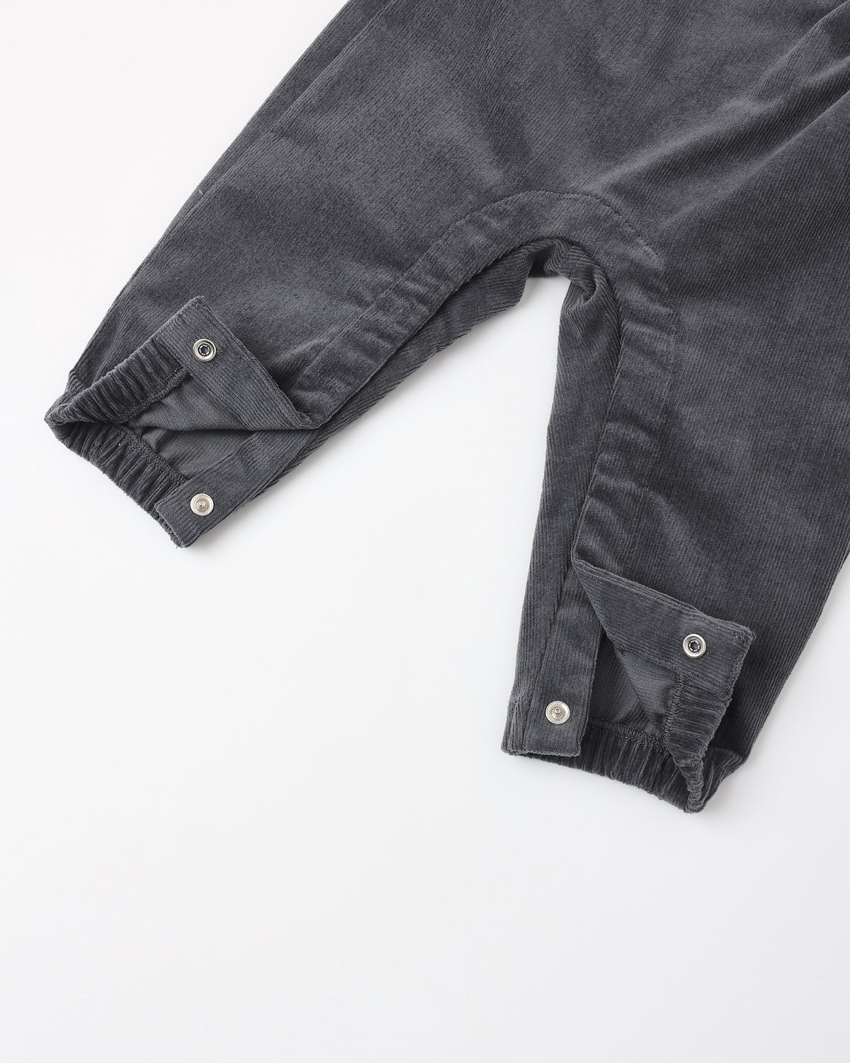 Close-up of dark gray corduroy pants with buttoned cuff details, laid flat on a white background.