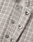 Close-up of a light gray and cream gingham plaid shirt with silver snap buttons.