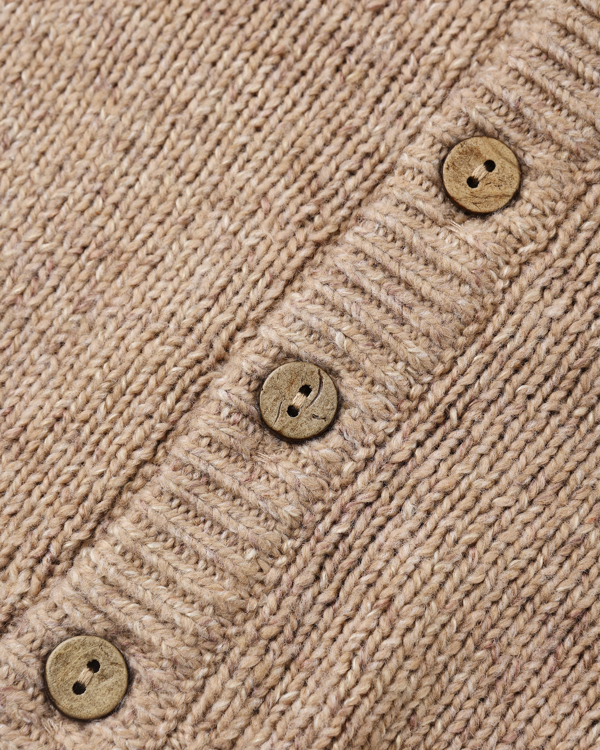 Close-up of a beige knit cardigan or sweater showing the ribbed texture and three round wooden buttons.
