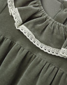 Close-up of a long-sleeve spruce green velour baby dress featuring a ruffled collar edged with delicate white lace.