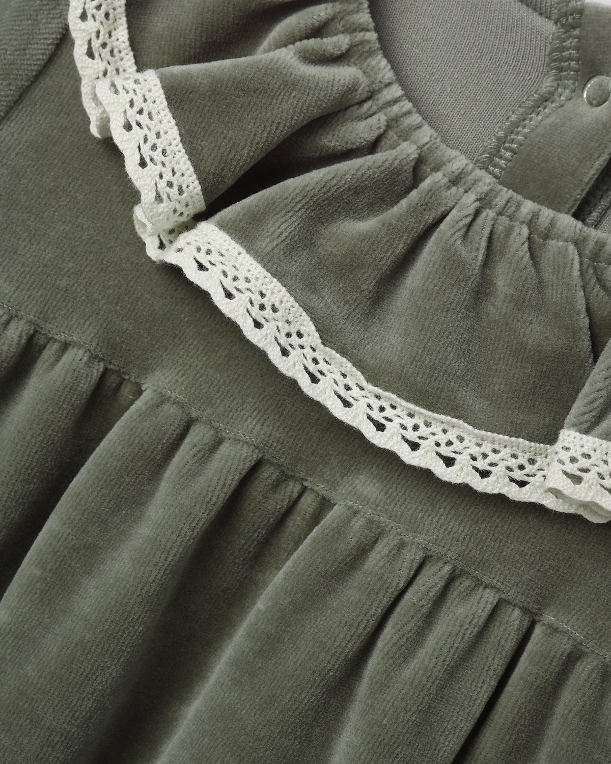 Close-up of a long-sleeve spruce green velour baby dress featuring a ruffled collar edged with delicate white lace.