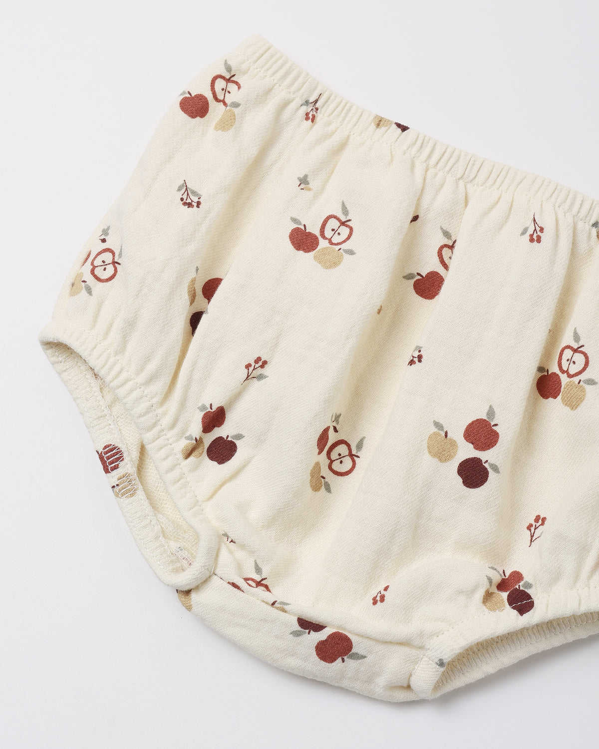 Cream-colored cotton diaper cover with a red and brown apple print, shown on a plain white background.