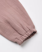 A close-up of a dusty rose or mauve-colored fabric garment, showing a gathered elastic cuff on a plain white background.