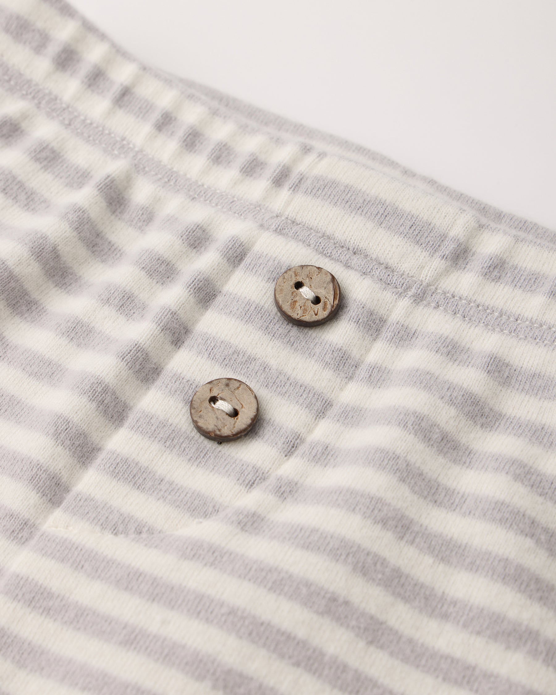 Close-up of the light gray and white fog stripe waffle knit fabric with two wooden buttons on the Quincy Mae Take Home Set.