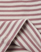 Close-up of a striped fabric with alternating dusty rose and off-white horizontal stripes, showing a folded corner with stitched edges.