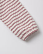 A close-up of a striped fabric sleeve or cuff with alternating dusty rose and off-white horizontal stripes, finished with a ribbed hem, on a light gray background.