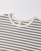 Close-up of a striped knit top with alternating gray and off-white horizontal stripes, featuring a cream ribbed crew neck and a small interior neck label reading 'GANT'.