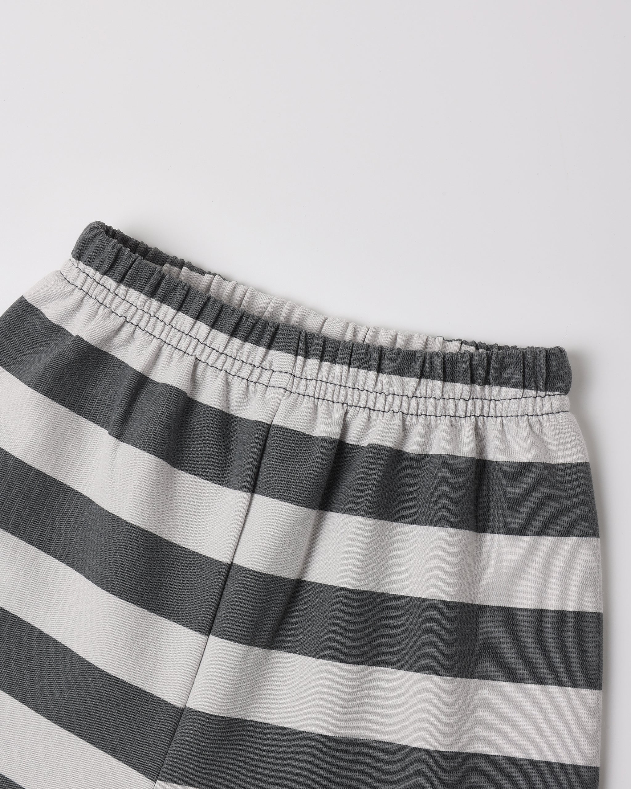 Close-up of a pair of striped shorts with horizontal dark gray and off-white stripes, featuring an elastic waistband.
