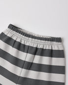 Close-up of a pair of striped shorts with horizontal dark gray and off-white stripes, featuring an elastic waistband.