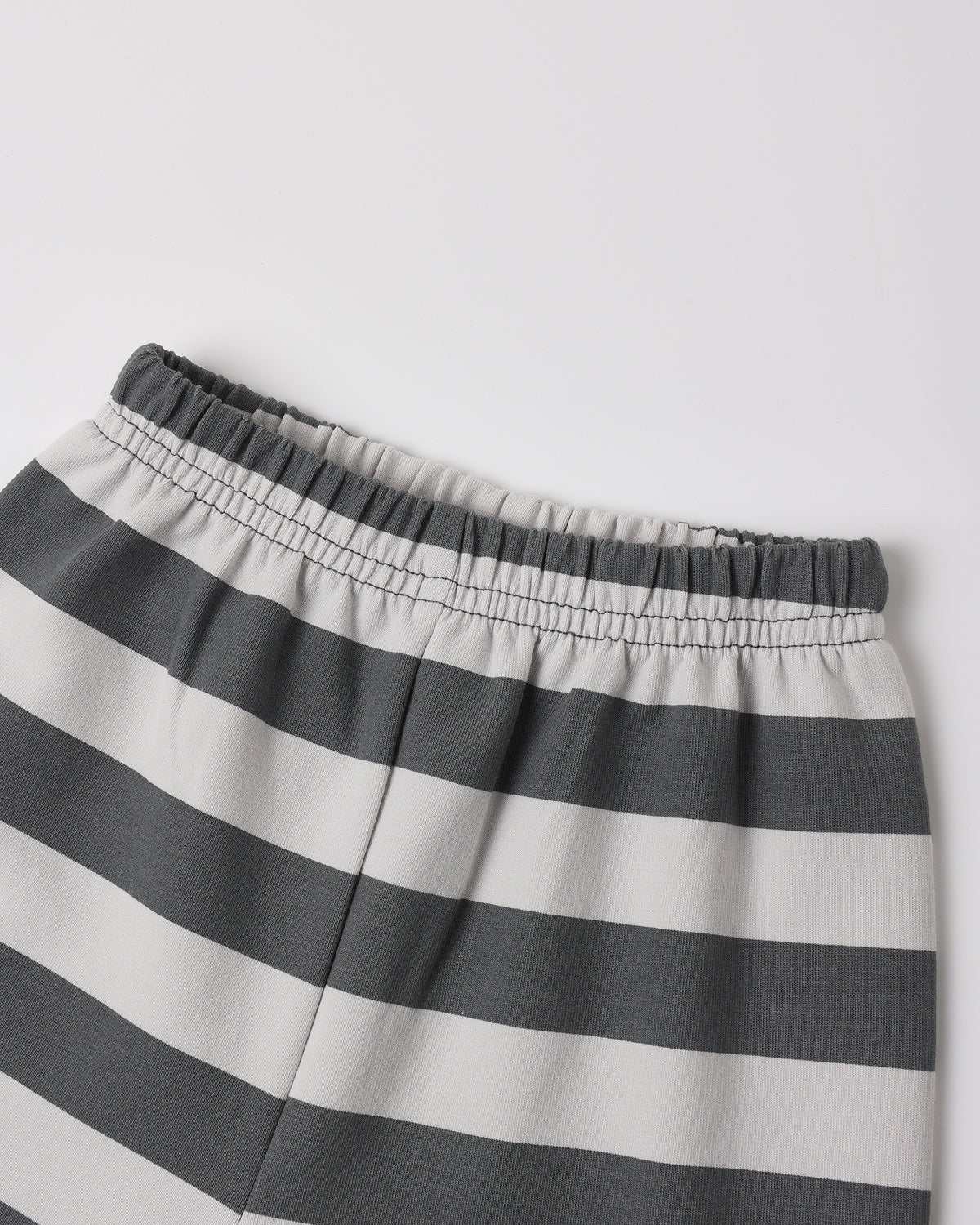 Close-up of a pair of striped shorts with horizontal dark gray and off-white stripes, featuring an elastic waistband.