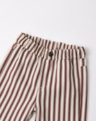 Close-up of striped trousers with vertical dark red and brown stripes on an off-white base, featuring an elastic waistband and a single dark button closure.