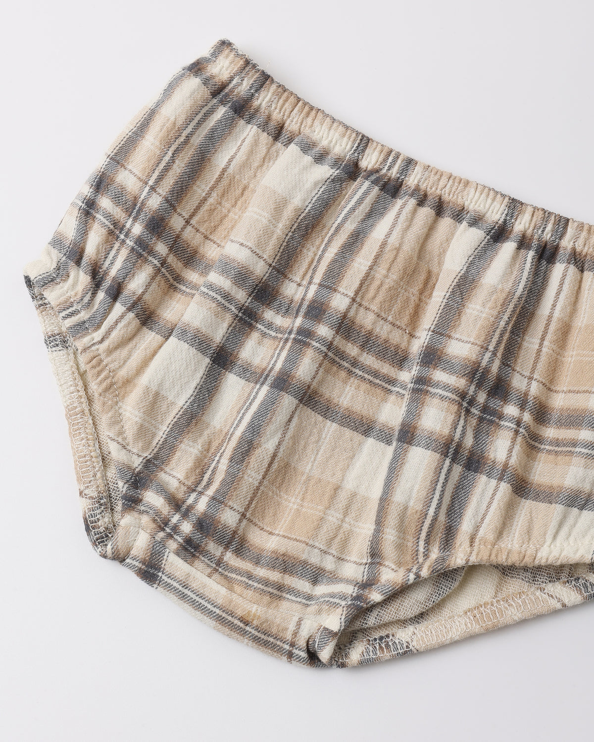 A pair of plaid baby bloomers in beige, brown, and gray, laid flat on a light gray background.