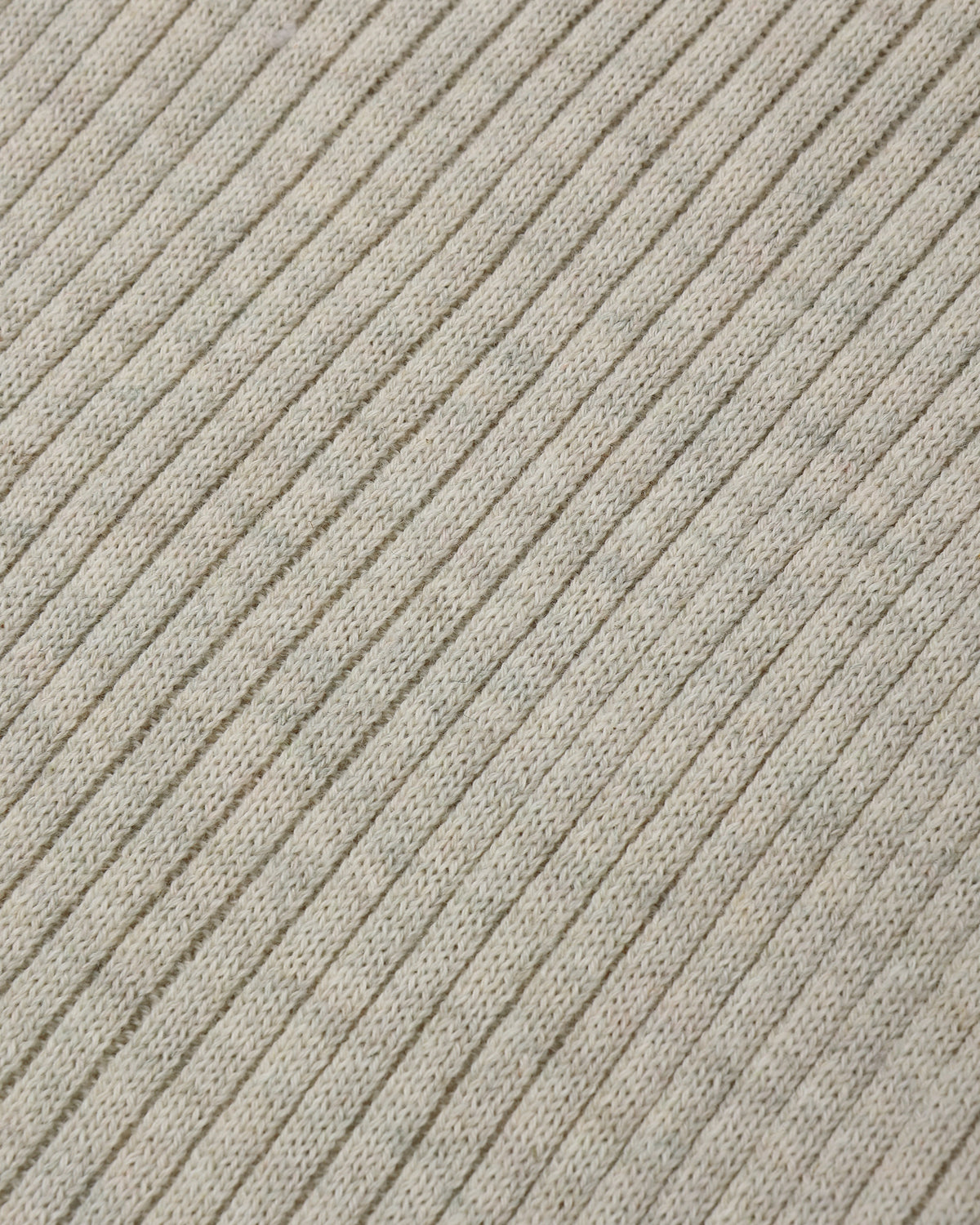 Close-up of a ribbed knit fabric in a light warm gray or oatmeal tone, showing the texture and pattern of the knit stitches.