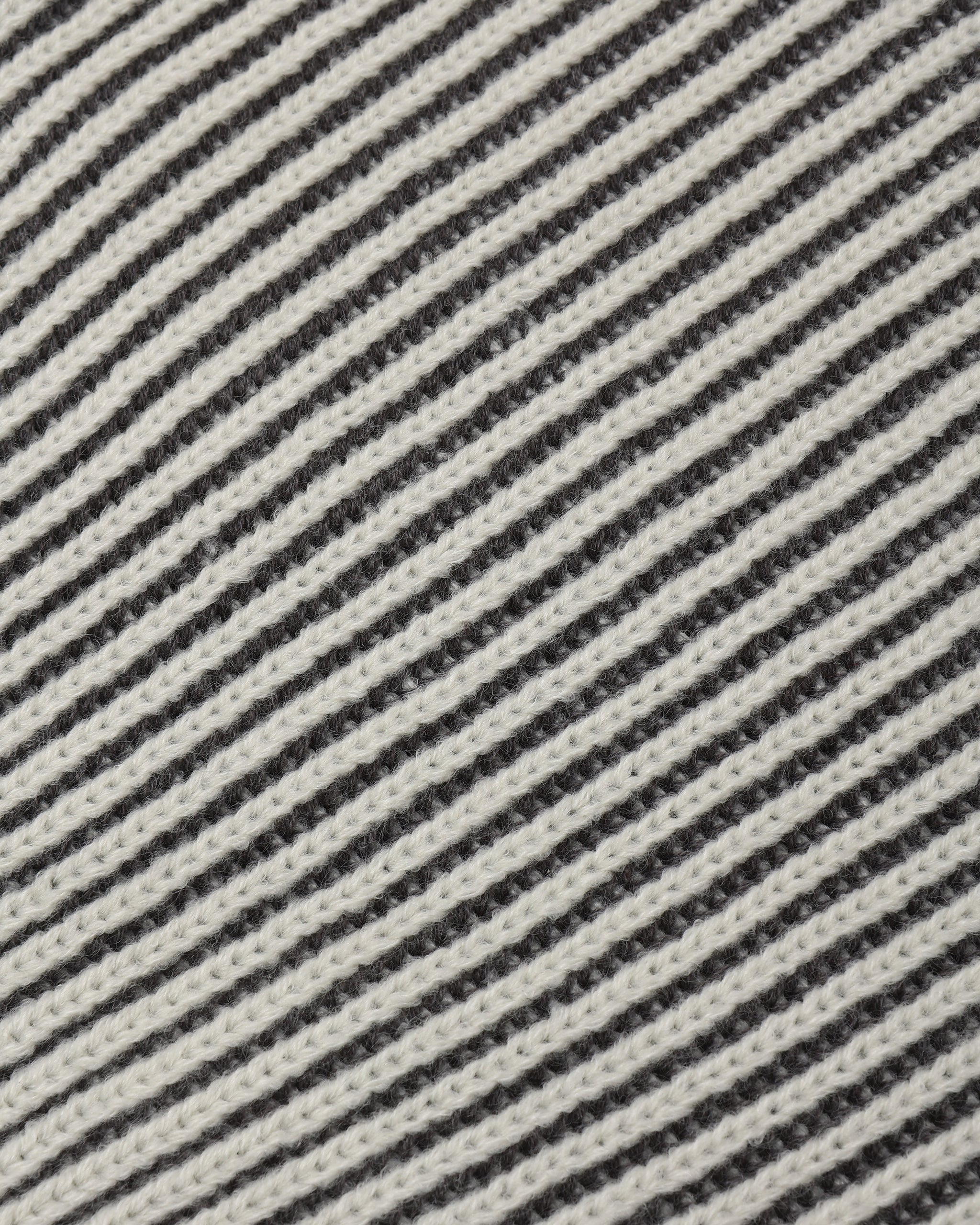 Close-up of a woven fabric with diagonal stripes in off-white and dark charcoal gray.