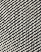 Close-up of a woven fabric with diagonal stripes in off-white and dark charcoal gray.