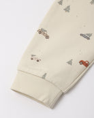 Close-up of cream-colored organic cotton fabric featuring a "Holiday Drive" print with tiny vintage cars and pine trees, showing a ribbed sleeve cuff.