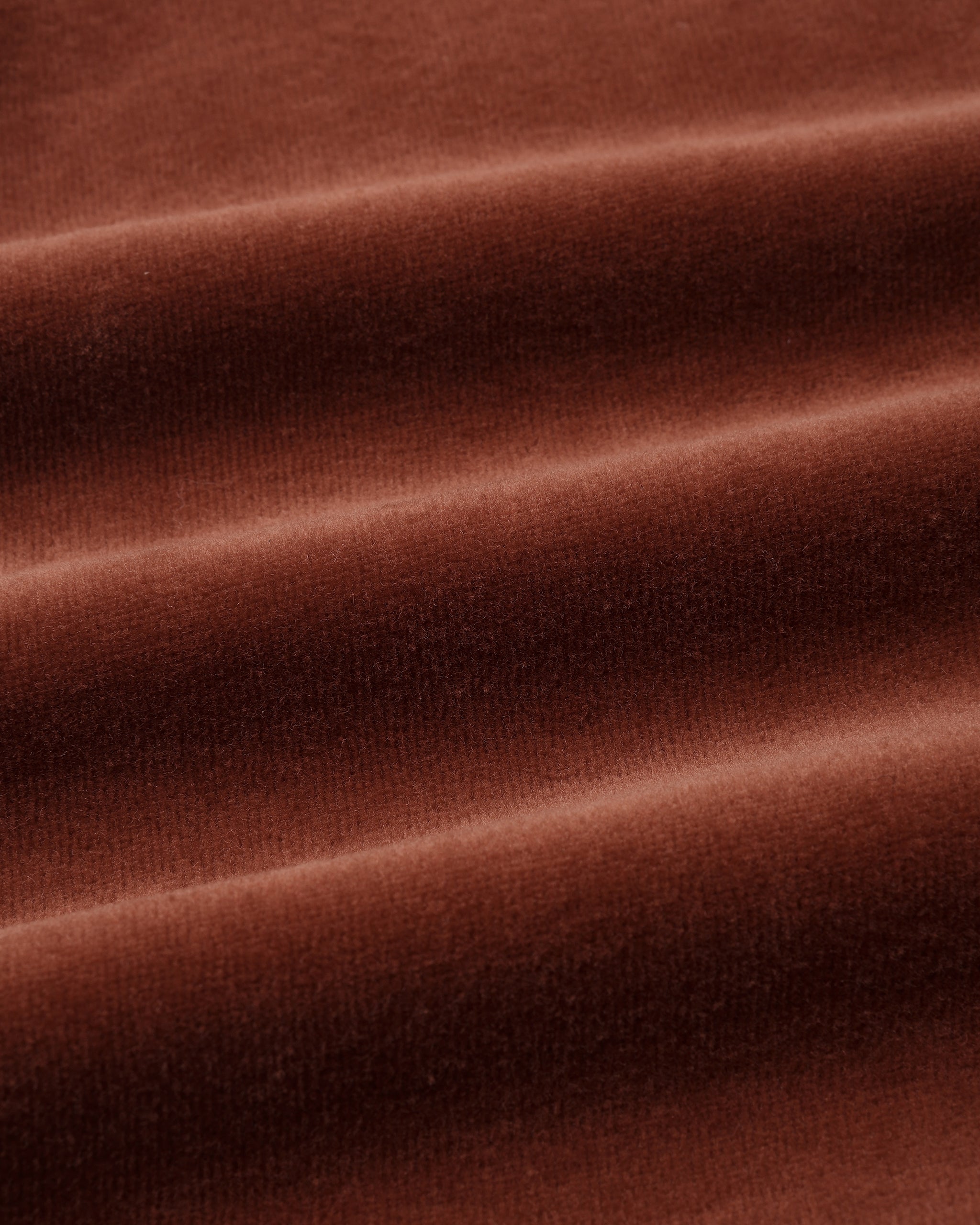 Close-up shot of soft, plush redwood brown velour fabric showing rich texture and gentle folds.
