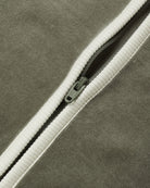 Close-up view of the diagonal white zipper and soft texture of the spruce green velour baby jumpsuit.