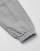 Close-up of a light gray fabric sleeve or cuff with an elastic gathered hem, shown on a plain light background.