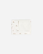 A folded white baby blanket or swaddle with a tiny scattered floral pattern, shown on a plain light gray background.