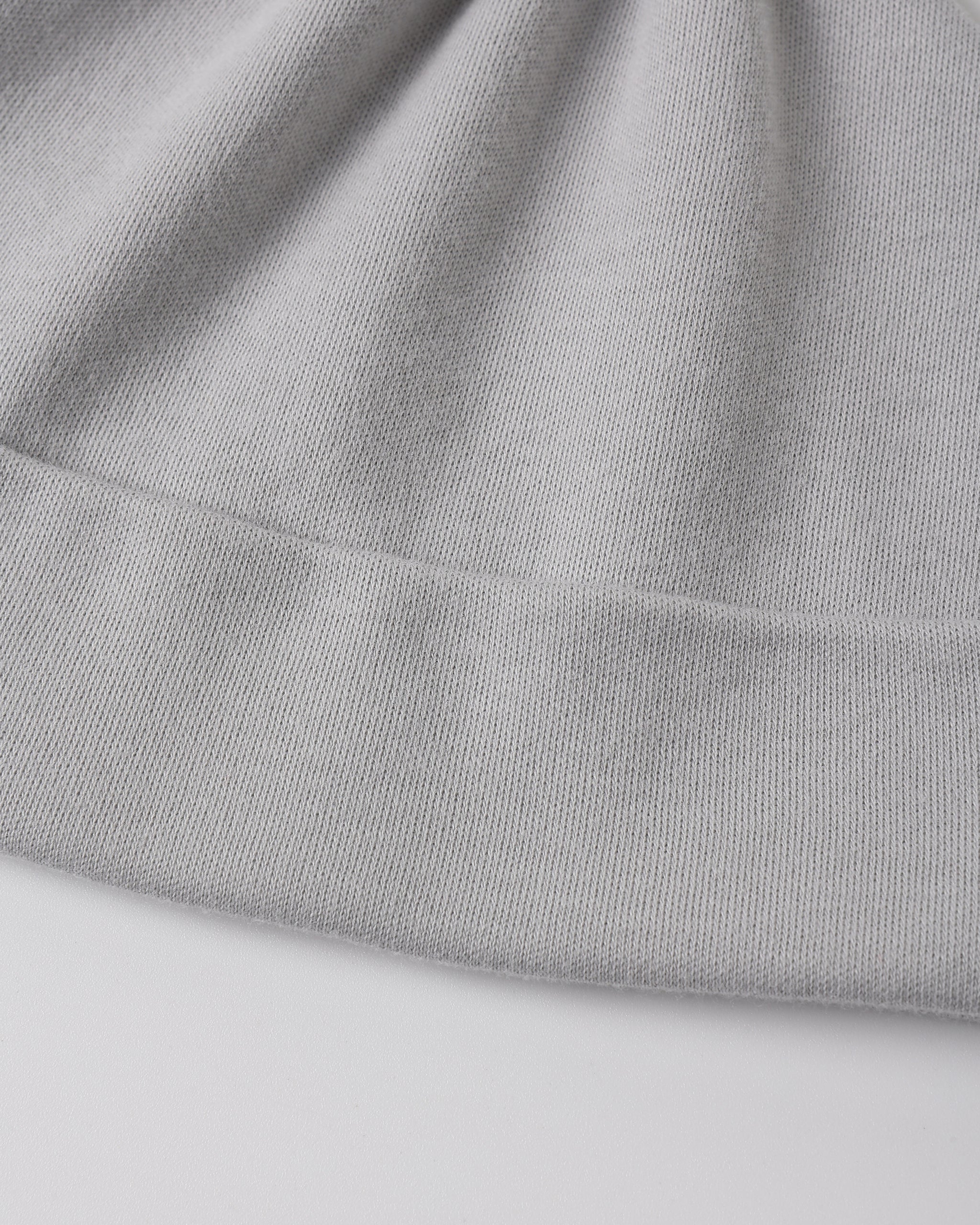 Close-up of a light gray ribbed knit fabric, showing the texture and folded edges of a garment or textile.