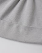 Close-up of a light gray ribbed knit fabric, showing the texture and folded edges of a garment or textile.