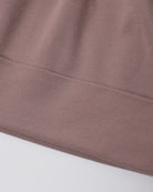 Close-up of a ribbed knit fabric in a muted dusty mauve-pink color, showing the texture and a folded hem against a plain light background.
