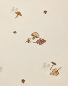 A close-up of a cream-colored surface with a scattered autumn-themed pattern featuring brown mushrooms, acorns, and oak leaves.