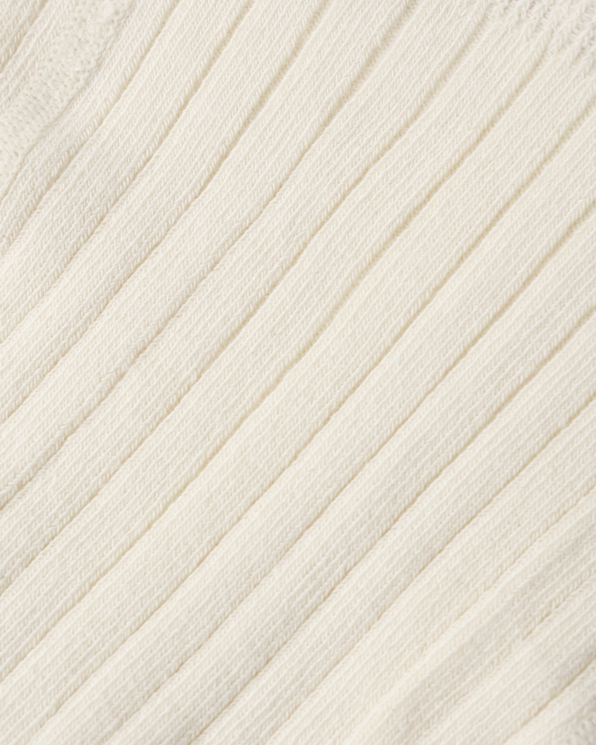 Close-up of a cream-colored ribbed knit fabric texture.