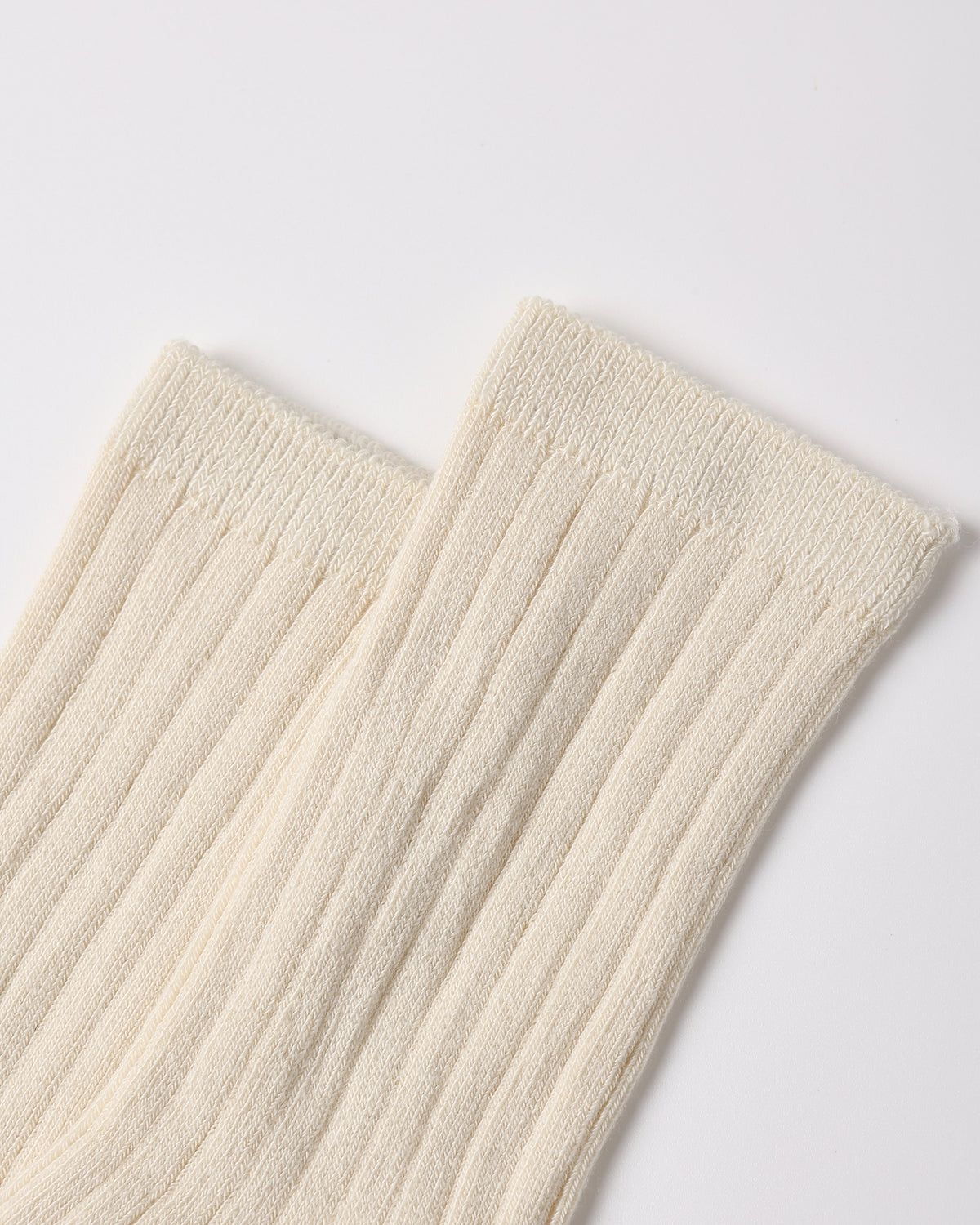 A close-up of a pair of ribbed cream-colored socks on a light gray background.