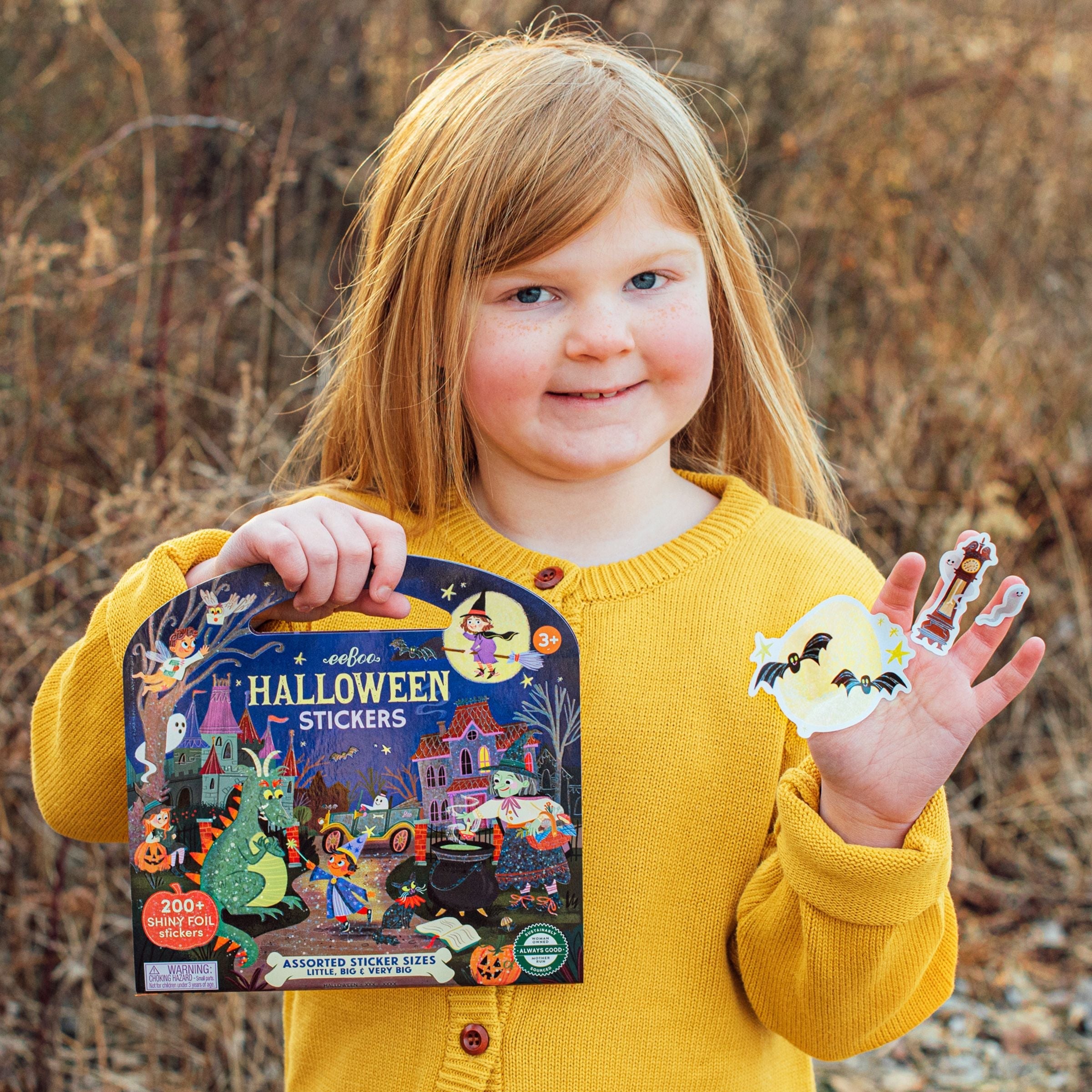 Child holding a package of Halloween stickers outdoors